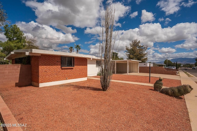 ranch-style home with a carport, brick siding, driveway, and fence