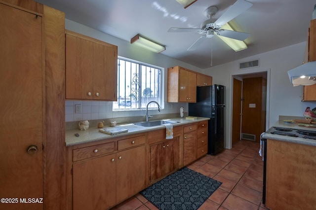 kitchen with a sink, visible vents, range with electric cooktop, and freestanding refrigerator