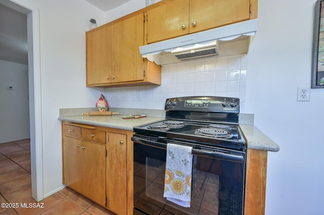 kitchen featuring light tile patterned flooring, decorative backsplash, light countertops, black range with electric cooktop, and under cabinet range hood