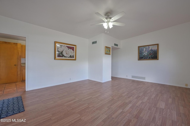 empty room featuring light wood-style floors, visible vents, and ceiling fan