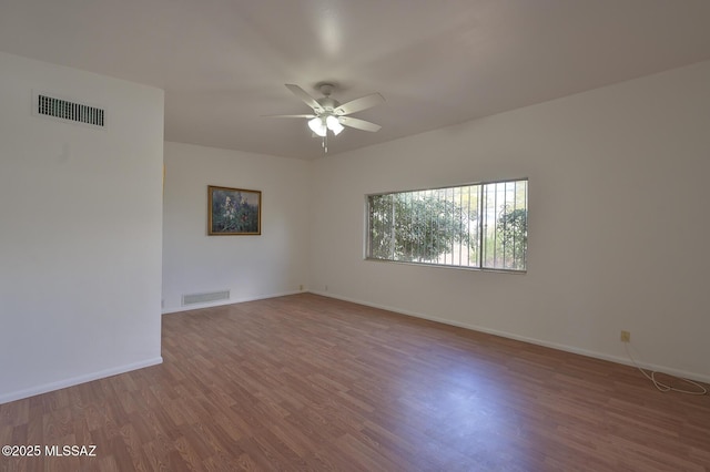 unfurnished room featuring baseboards, wood finished floors, visible vents, and ceiling fan