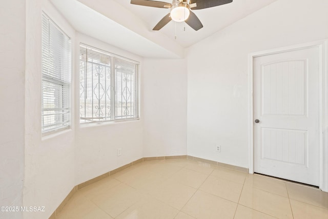 unfurnished room with tile patterned flooring, a ceiling fan, and baseboards