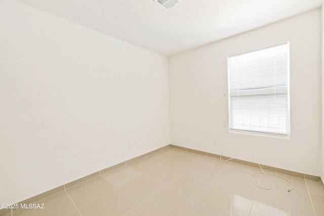 empty room featuring visible vents, baseboards, and light tile patterned flooring