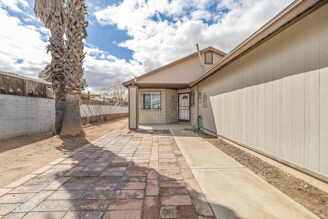 view of exterior entry with a patio area and fence