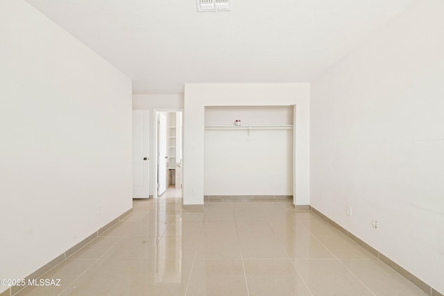 unfurnished bedroom with light tile patterned floors, visible vents, a closet, and baseboards