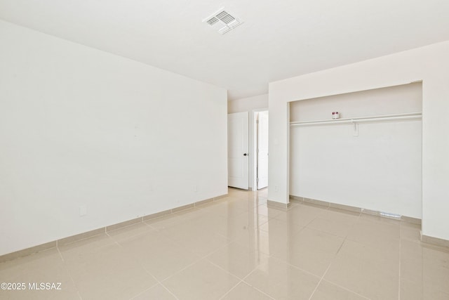 unfurnished bedroom featuring light tile patterned floors, visible vents, and a closet