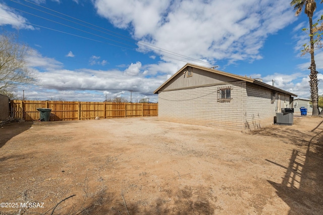 view of side of home featuring central air condition unit and fence