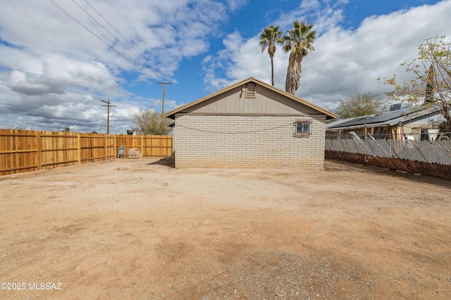 view of side of home featuring brick siding and fence