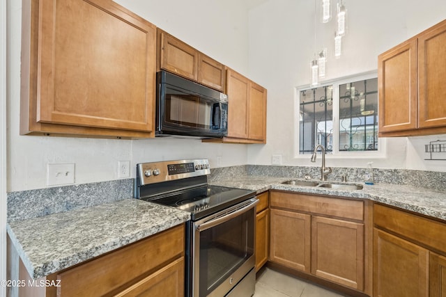 kitchen featuring black microwave, light stone countertops, stainless steel range with electric stovetop, brown cabinetry, and a sink