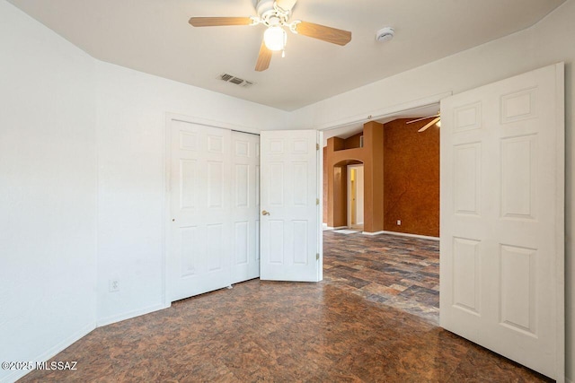 unfurnished bedroom featuring baseboards, visible vents, arched walkways, and a closet