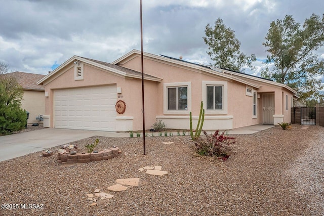 ranch-style home with a gate, solar panels, an attached garage, stucco siding, and concrete driveway