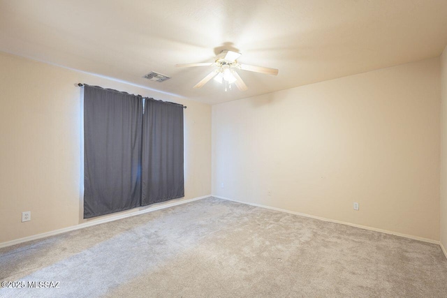 carpeted spare room with baseboards, visible vents, and ceiling fan