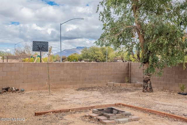 view of yard featuring a mountain view, an outdoor fire pit, and a fenced backyard