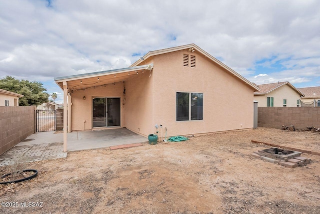 rear view of house featuring a gate, stucco siding, a patio area, and fence