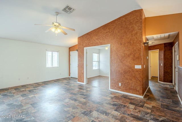 empty room with visible vents, a ceiling fan, stone finish flooring, and lofted ceiling