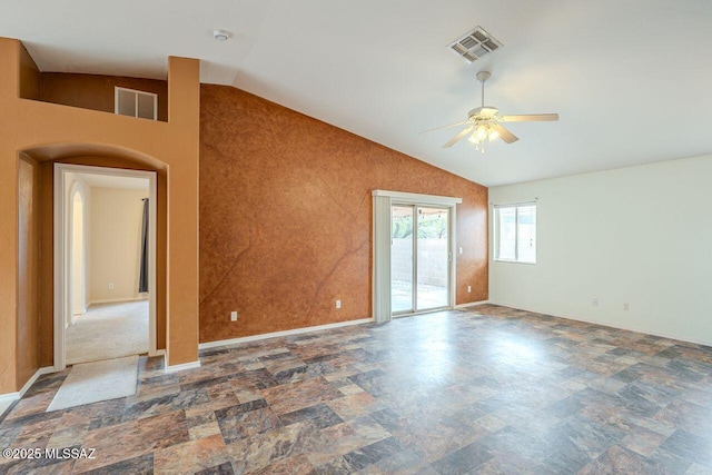 spare room featuring vaulted ceiling, stone finish floor, a ceiling fan, and visible vents