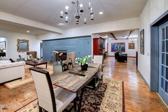 dining area featuring an inviting chandelier, beamed ceiling, light wood-style floors, and baseboards