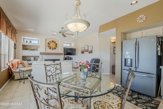 dining area with a fireplace, light tile patterned floors, baseboards, and a ceiling fan