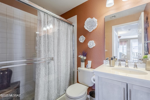 full bathroom featuring vanity, a textured wall, a shower with curtain, toilet, and visible vents