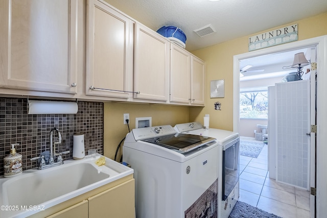 laundry room featuring visible vents, a sink, cabinet space, washing machine and clothes dryer, and light tile patterned flooring