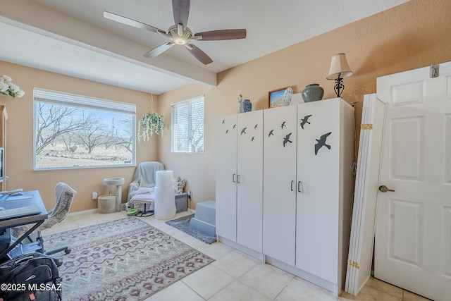 home office featuring ceiling fan, beamed ceiling, and light tile patterned floors