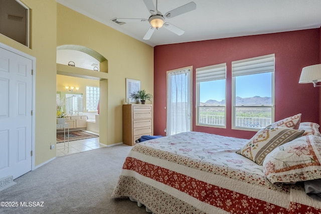 tiled bedroom with ensuite bath, visible vents, vaulted ceiling, carpet floors, and a mountain view