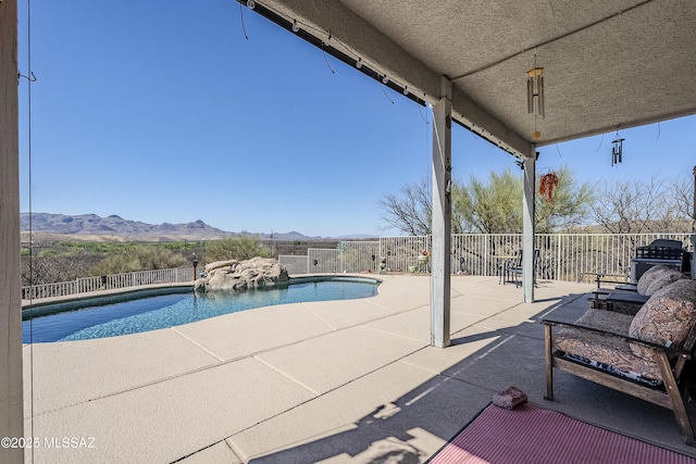 view of swimming pool featuring a patio, a mountain view, a fenced in pool, and fence