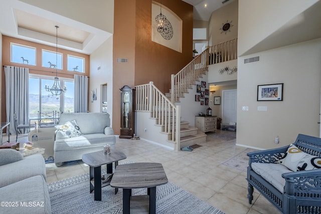 living room featuring visible vents, stairway, a tray ceiling, and a chandelier