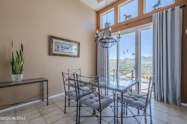 dining area with a towering ceiling, a notable chandelier, baseboards, a mountain view, and light tile patterned flooring