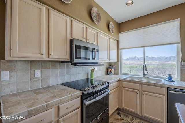 kitchen with tile countertops, a sink, light brown cabinetry, and appliances with stainless steel finishes