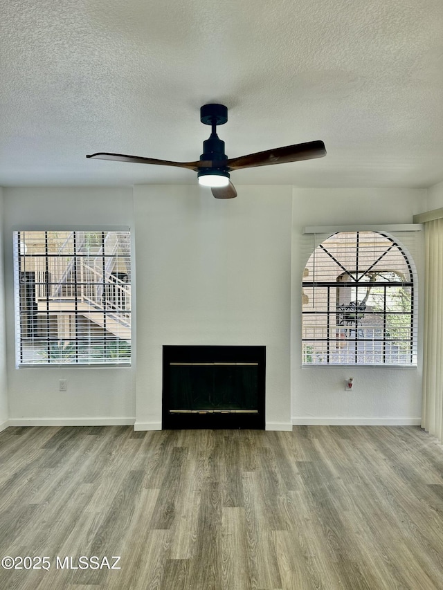 unfurnished living room featuring a ceiling fan, wood finished floors, and a healthy amount of sunlight