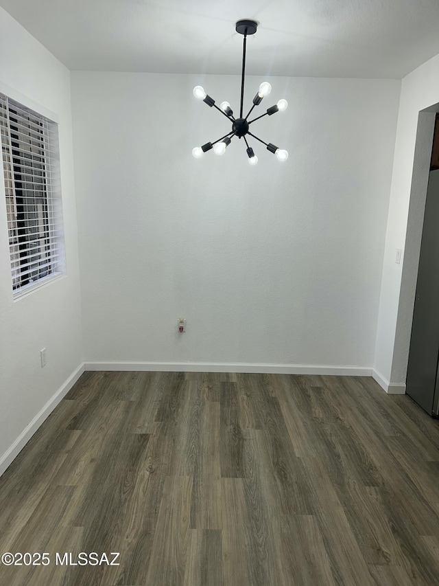 unfurnished dining area featuring baseboards, dark wood-type flooring, and an inviting chandelier