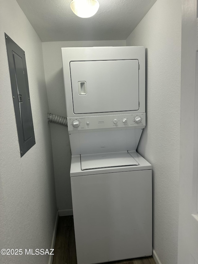 washroom with electric panel, baseboards, wood finished floors, and stacked washer / dryer