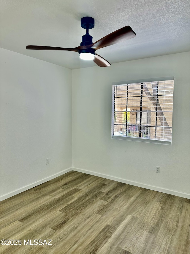 empty room featuring baseboards, a textured ceiling, wood finished floors, and a ceiling fan