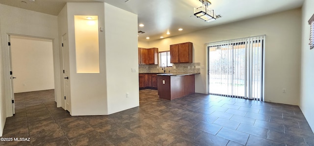 kitchen with dark countertops, visible vents, backsplash, recessed lighting, and brown cabinets