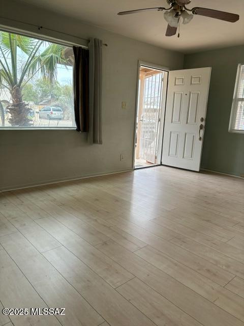 foyer entrance with baseboards, light wood-type flooring, and ceiling fan