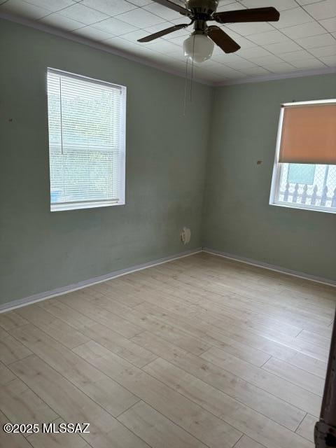 spare room featuring ceiling fan, wood finished floors, baseboards, and ornamental molding