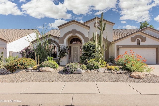 mediterranean / spanish-style home featuring stucco siding, a tiled roof, an attached garage, and concrete driveway