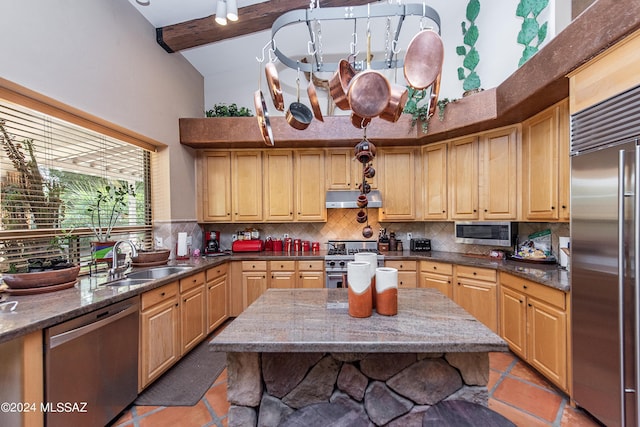 kitchen featuring lofted ceiling with beams, premium appliances, a sink, under cabinet range hood, and tasteful backsplash