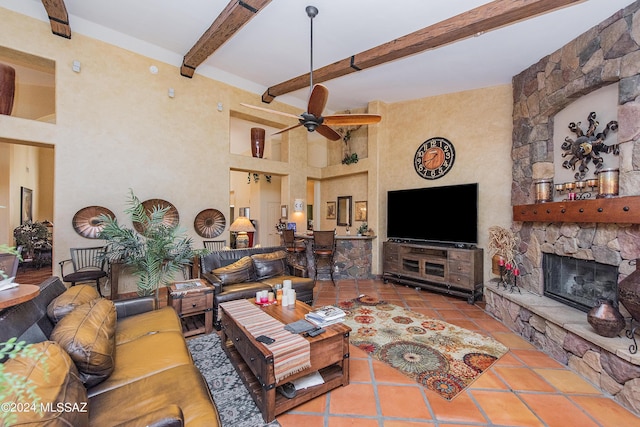 tiled living area with beamed ceiling, a fireplace, a towering ceiling, and ceiling fan