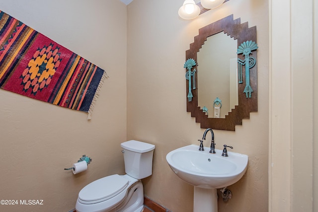 half bath with a sink, toilet, and a chandelier