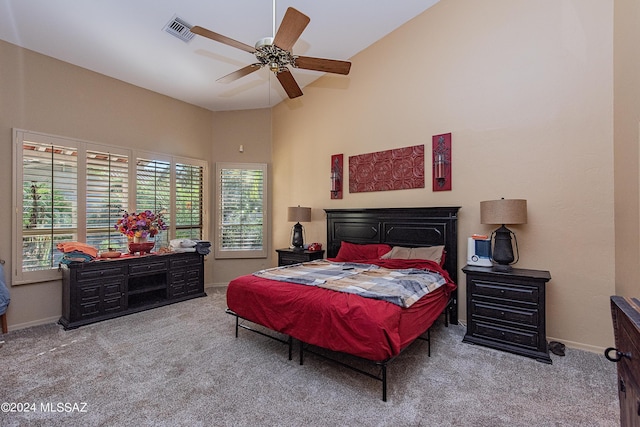 carpeted bedroom with visible vents, baseboards, a high ceiling, and a ceiling fan