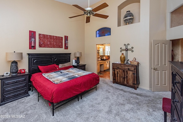 bedroom with ensuite bath, carpet, a towering ceiling, and ceiling fan