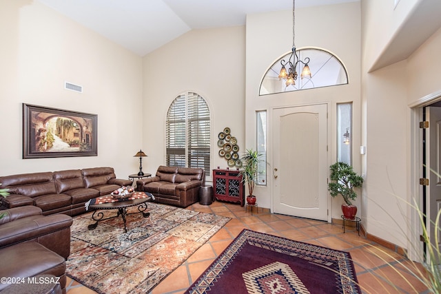 tiled living area with visible vents, baseboards, high vaulted ceiling, and a chandelier