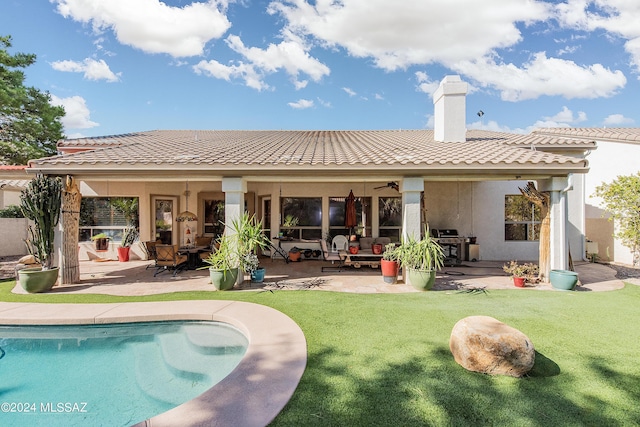 back of property featuring stucco siding, a lawn, a patio, a chimney, and a tiled roof