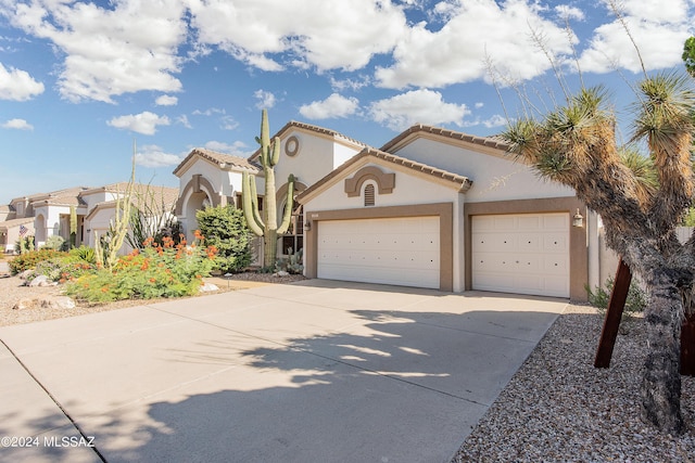 mediterranean / spanish house with a tile roof, stucco siding, concrete driveway, and a garage