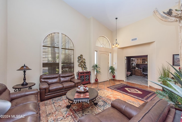 tiled living room featuring visible vents, a notable chandelier, and high vaulted ceiling