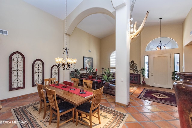 dining room featuring baseboards, an inviting chandelier, arched walkways, tile patterned flooring, and a towering ceiling