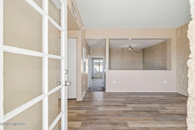 spare room with visible vents, french doors, a textured ceiling, and wood finished floors