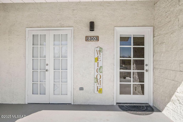 view of exterior entry with stucco siding and french doors